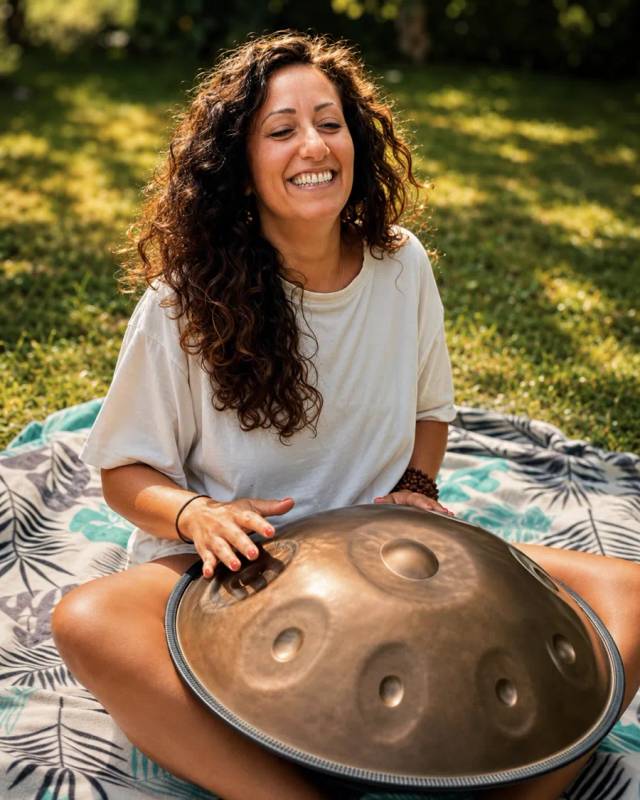 Maharani Singh lächelt mit einer Handpan in der Natur